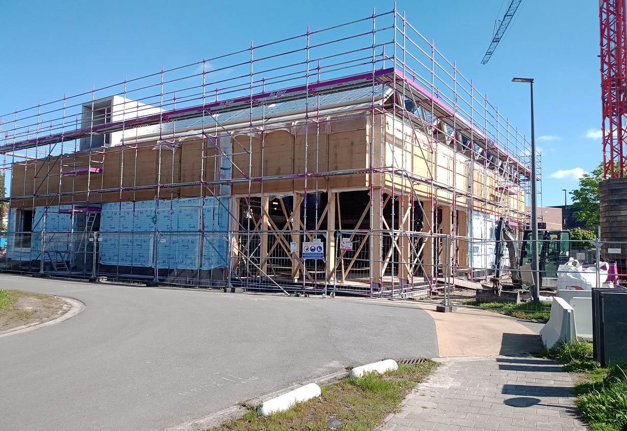 Gebouw in opbouw met steigers en houten constructiedelen voor de turnzaal Sint-Amands.